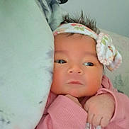 Joanna is registered to the contest to win money with this photo: baby, infant, headband, pink_sweater, hand, face, person, indoor, blanket, curly_hair, holding, wall, hat, shelf, decoration, portrait, cute, soft_lighting, closeup, newborn