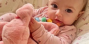 Kiara is registered to the contest to win money with this photo: baby, infant, plush_toy, pink_clothing, blanket, soft_toy, cute, child, face, portrait, indoors, cozy, sleeping_bag, comfort, resting, young_child, toddler, holding, warm, cuddly