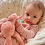 baby, infant, plush_toy, pink_clothing, blanket, soft_toy, cute, child, face, portrait, indoors, cozy, sleeping_bag, comfort, resting, young_child, toddler, holding, warm, cuddly