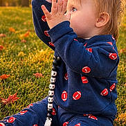 Jaxson joined the competition — help win amazing prizes! child, toddler, baby, outdoor, grass, park, autumn, sunset, golden_hour, portrait, sitting, hands_raised, profile, blond_hair, blue_clothing, jumpsuit, red_socks, football_pattern, fallen_leaves, nature
