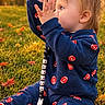 autumn, baby, blond_hair, blue_clothing, child, fallen_leaves, football_pattern, golden_hour, grass, hands_raised, jumpsuit, nature, outdoor, park, portrait, profile, red_socks, sitting, sunset, toddler