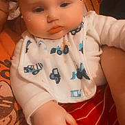 Jaxson is registered to the contest to win money with this photo: baby, infant, close_up, bib, truck_pattern, striped_pants, chubby_cheeks, hand, glasses, partial_adult, heart_emoji, indoor, wooden_background, filtered, portrait, cute, sleepy, sitting, red_pants, white_onesie
