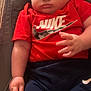 baby, blond_hair, car_seat, casual_clothing, chubby_cheeks, close_up, clothing, cushion, cute, face, hand, indoor, infant, navy_pants, nike_logo, portrait, red_shirt, relaxed, sleepy, toddler