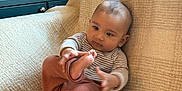 Ansh joined the competition — help win amazing prizes! baby, child, infant, couch, blanket, striped_clothing, ribbed_pants, barefoot, wicker_basket, home_interior, curtains, soft_lighting, exploring, sitting, indoors, cozy, furniture, cute, person, relaxed