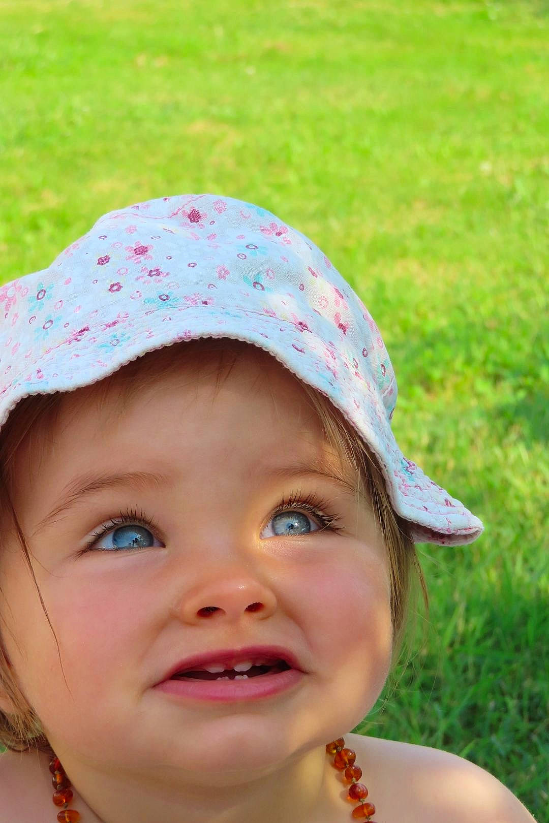 Norah participe au concours pour gagner de l'argent avec cette photo : cap, chin, cool, eye, grass, happy, hat, head, headgear, headwear, human_body, lip, mammal, nose, people_in_nature, person, photograph, pink, skin, smile