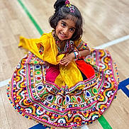 Qiyara joined the competition — help win amazing prizes! child, girl, smiling, traditional_clothing, colorful_dress, patterned_fabric, sitting, wooden_floor, sports_court_lines, hair_accessories, happy, portrait, indoor, cultural, festive, young, cute, posing, bright_colors, accessories