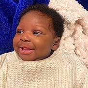 Elaïla a rejoint le concours — aidez-le/la à gagner de superbes lots ! baby, smiling, face, blanket, knit_sweater, cozy, infant, happy, cute, portrait, child, soft_texture, blue_blanket, cream_blanket, warm, closeup, indoors, young_child, head, expression