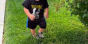 Luciano joined the competition — help win amazing prizes! toddler, child, grass, lawn, tshirt, black_clothing, shorts, shoes, walking, outdoor, greenery, bush, leafy_plants, sidewalk, fence, suburban, portrait, young_child, nature, casual_clothing