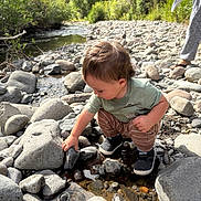 Luciano joined the competition — help win amazing prizes! casual_clothing, child, creek, curiosity, daylight, exploration, footwear, greenery, hand, nature, outdoor, person, riverbed, rocks, shoes, squatting, sunlight, toddler, tool, water