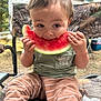camouflage, chair, child, clothing, cute, eating, face, food, fruit, green_shirt, hands, happy, nature, outdoor, picnic, striped_pants, summer, toddler, trees, watermelon