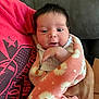 Vida is registered to the contest to win money with this photo: adult, arm, baby, blanket, clothing, couch, cozy, cute, face, floral_pattern, gaze, hand, indoor, infant, newborn, person, pink, portrait, resting, soft_texture