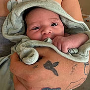 Vida joined the competition — help win amazing prizes! baby, infant, towel, hooded_towel, tattoo, hand, skin, indoor, person, face, cute, newborn, human, wrapped, cozy, closeup, expression, holding, soft, curious