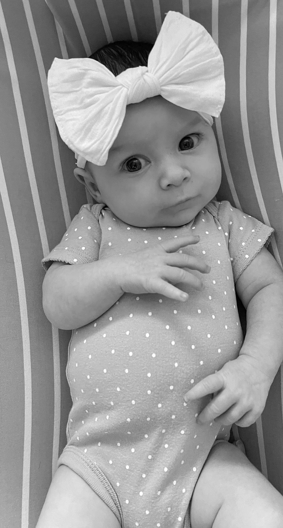 Magnolia is registered to the contest to win money with this photo: arm, baby_toddler_clothing, black, black_and_white, dress, facial_expression, gesture, hairstyle, hand, headwear, human_body, iris, lip, organ, person, photograph, product, skin, sleeve, standing