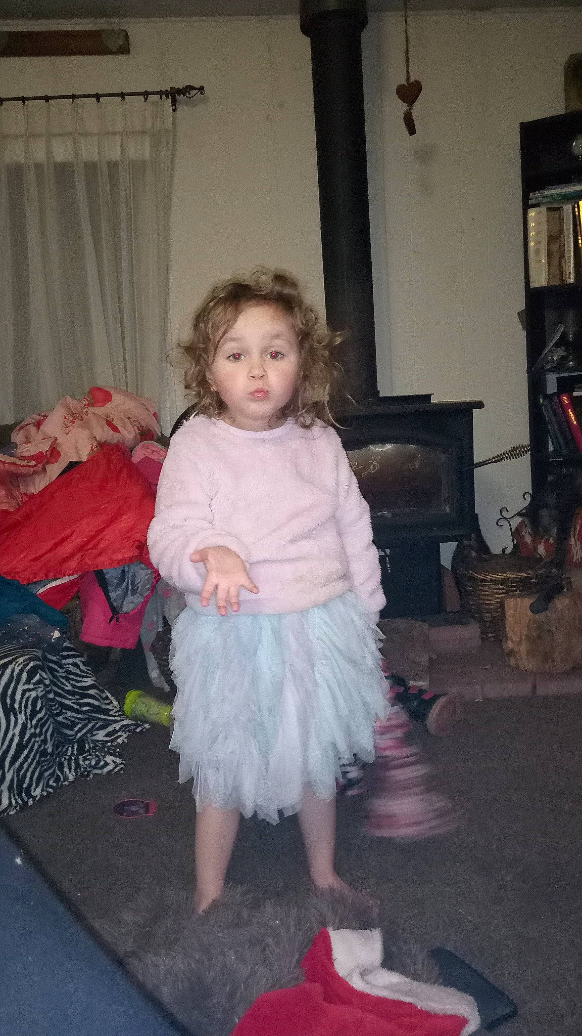 Lillian is registered to the contest to win money with this photo: baby_toddler_clothing, child, costume, curtain, day_dress, event, floor, flooring, fun, fur, hardwood, houseplant, iris, magenta, person, picture_frame, pink, shelf, sitting, surprise