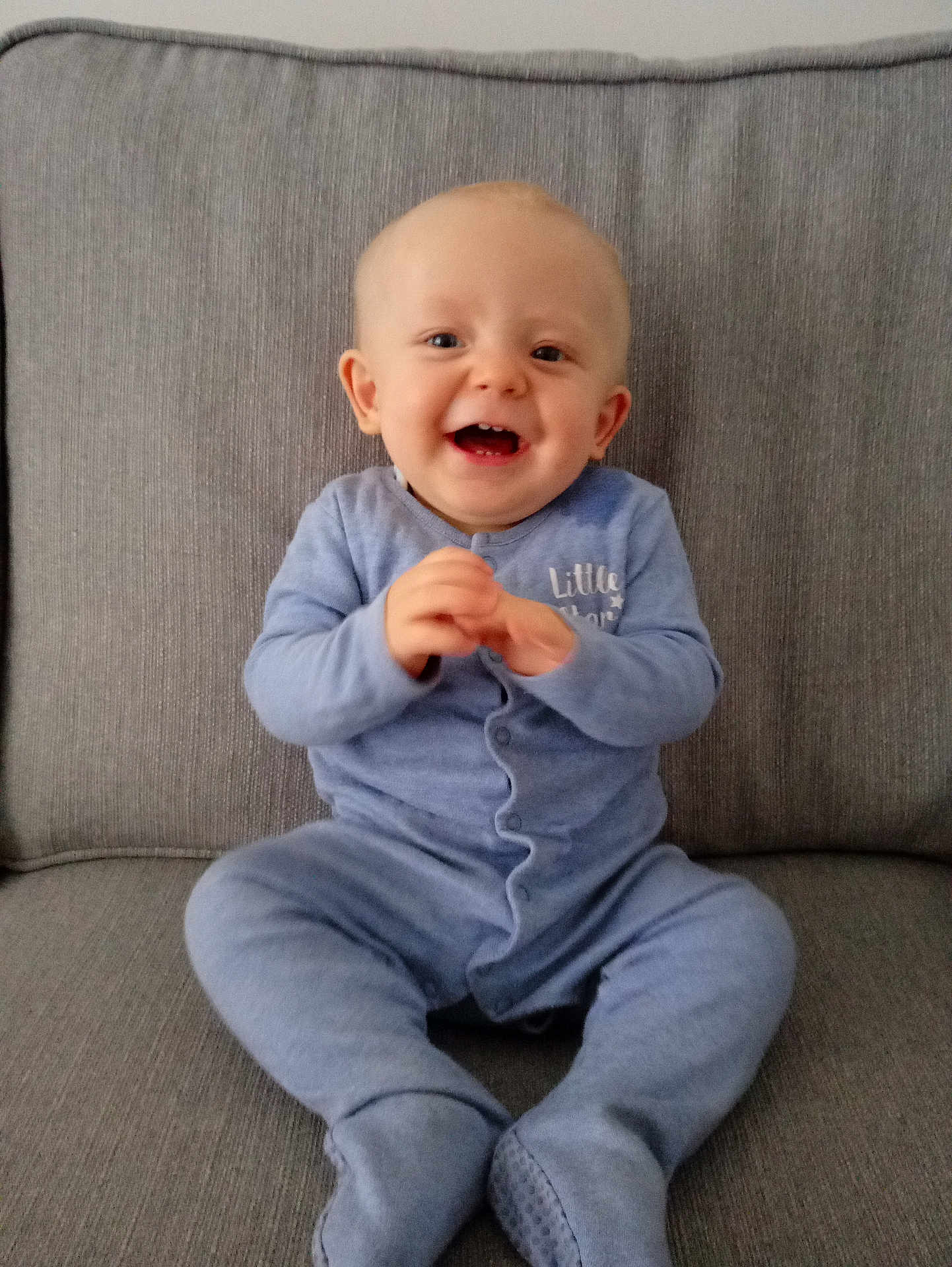 Andre joined the competition — help win amazing prizes! baby, child, smiling, blue_onesie, sitting, clapping_hands, happy, face, cute, infant, couch, furniture, indoors, cozy, young_child, portrait, expression, skin, head, eyes