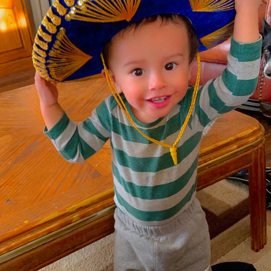 Javier is registered to the contest to win money with this photo: boy, cap, child, clothing, costume, face, footwear, furniture, hardwood, hat, head, hosiery, male, pants, person, photography, portrait, sock, sombrero, wood