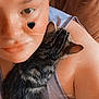 casual_clothing, cat, closeup, comfort, couch, cute, eyebrow_piercing, face, feline, heart_sticker, indoor, kitten, person, pet, portrait, relaxation, shoulder, skin, snuggling, tabby_cat