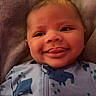 Caspian joined the competition — help win amazing prizes! baby, infant, child, smiling, happy, portrait, face, eyes, cheeks, indoors, blanket, cozy, pajamas, onesie, zipper, animal_print, elephant, dinosaur, lying_down, close_up