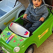 Saad joined the competition — help win amazing prizes! toddler, child, denim_hoodie, toy_car, green_car, unicorn_stickers, stars, indoor, floor_tiles, small_wheels, steering_wheel, cute_expression, casual_clothing, playtime, vehicle_toy, kid_playing, seat, hood, bright_colors, imaginative_play
