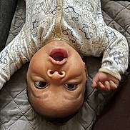 Rashawn joined the competition — help win amazing prizes! animal_pattern, baby, child, curious, cute, expression, face, hand, head, indoor, infant, newborn, onesie, person, quilted_blanket, resting, soft_lighting, upside_down, wide_eyes, young