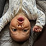 animal_pattern, baby, child, curious, cute, expression, face, hand, head, indoor, infant, newborn, onesie, person, quilted_blanket, resting, soft_lighting, upside_down, wide_eyes, young