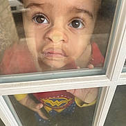 Wrenley joined the competition — help win amazing prizes! child, toddler, face, window, glass, reflection, curious, wonder_woman, costume, red_clothing, yellow_clothing, blue_clothing, indoor, hand, expression, closeup, portrait, person, young_child, casual