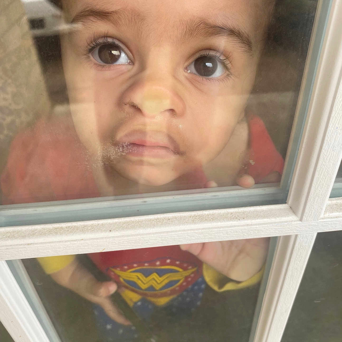 Wrenley joined the competition — help win amazing prizes! blue_clothing, casual, child, closeup, costume, curious, expression, face, glass, hand, indoor, person, portrait, red_clothing, reflection, toddler, window, wonder_woman, yellow_clothing, young_child