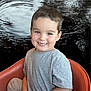 child, smiling, boy, short_hair, gray_shirt, orange_chair, indoor, portrait, happy, seated, ripples, water, background, casual_clothing, cute, face, person, young, relaxed, light