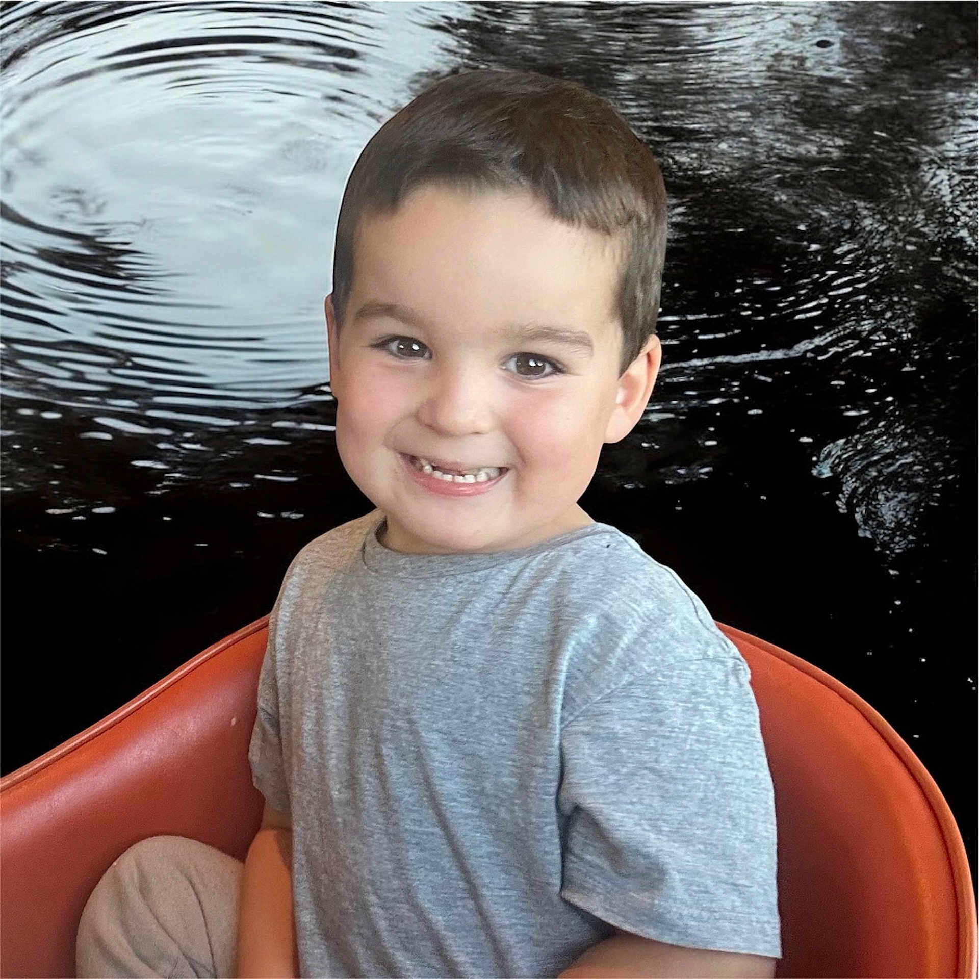 Léo a rejoint le concours — aidez-le/la à gagner de superbes lots ! background, boy, casual_clothing, child, cute, face, gray_shirt, happy, indoor, light, orange_chair, person, portrait, relaxed, ripples, seated, short_hair, smiling, water, young