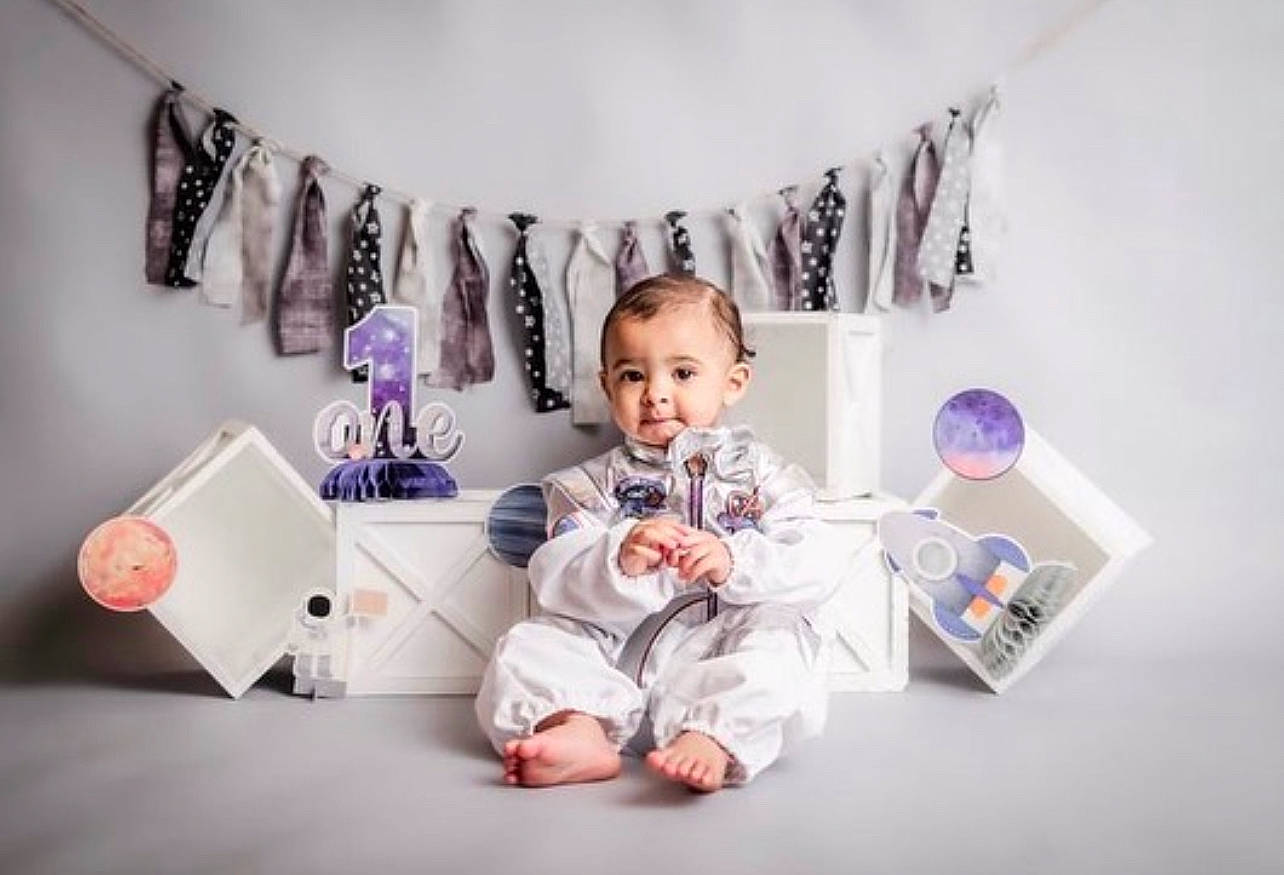 Apollo is registered to the contest to win money with this photo: art, baby, baby_toddler_clothing, ceiling, fashion, fashion_accessory, font, illustration, lighting, lighting_accessory, magenta, paper, person, pink, purple, room, sitting, sleeve, t_shirt, textile