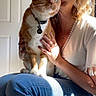 blue_jeans, casual, cat, collar, curious, door, fingernails, hand, hat, indoor, lap, necklace, orange_cat, pet, portrait, shadow, sitting, sunlight, white_top, woman