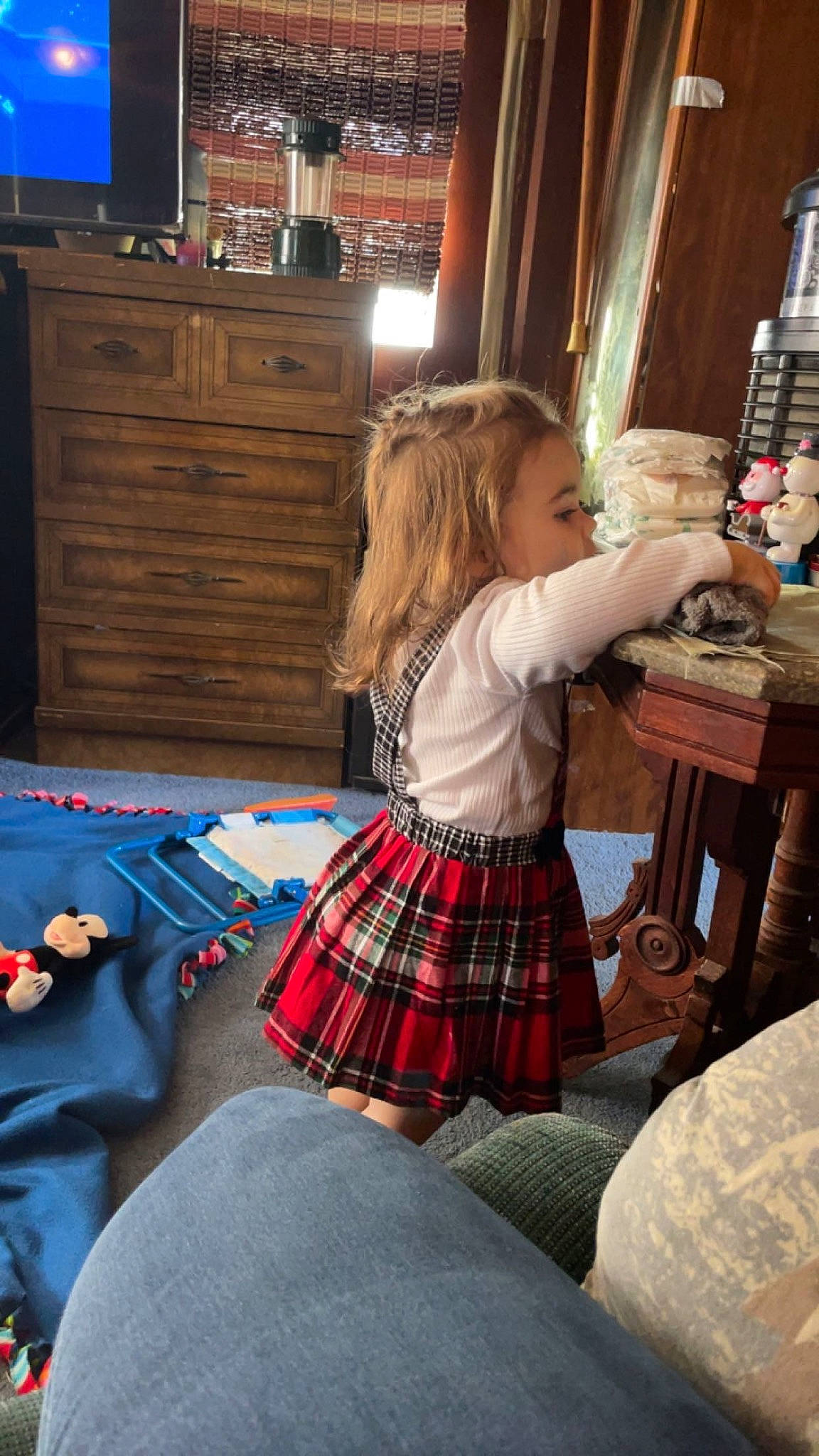 Scarlet is registered to the contest to win money with this photo: cabinetry, chest_of_drawers, child, christmas, drawer, event, fun, holiday, lighting, living_room, pattern, person, plaid, sock, standing, tartan, television, textile, toddler, tree