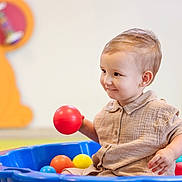 Malhonn a rejoint le concours — aidez-le/la à gagner de superbes lots ! toddler, child, smiling, ball, blue_pool, playroom, indoor, toy, colorful, happy, cute, short_sleeve_shirt, beige_clothing, young_child, play, fun, person, face, hand, seated