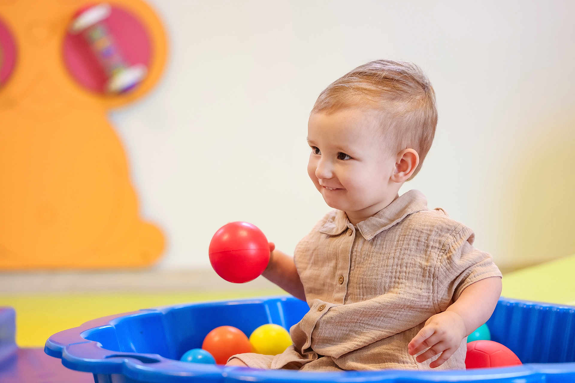 Malhonn a rejoint le concours — aidez-le/la à gagner de superbes lots ! toddler, child, smiling, ball, blue_pool, playroom, indoor, toy, colorful, happy, cute, short_sleeve_shirt, beige_clothing, young_child, play, fun, person, face, hand, seated