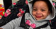 Diana is registered to the contest to win money with this photo: baby, blanket, car_seat, child, clothing, cozy, cute, face, floral_pattern, happy, hoodie, indoor, infant, pacifier, person, portrait, seatbelt, smile, toddler, toy