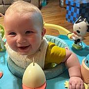 Slade joined the competition — help win amazing prizes! baby, smiling, child, indoor, toy, activity_center, happy, person, face, furniture, living_room, floor, sitting, playful, colorful, cute, young_child, infant, clothing, hand