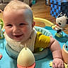 baby, smiling, child, indoor, toy, activity_center, happy, person, face, furniture, living_room, floor, sitting, playful, colorful, cute, young_child, infant, clothing, hand