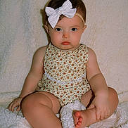 Harper joined the competition — help win amazing prizes! baby, child, infant, bow, headband, romper, floral_pattern, blanket, soft_texture, cute, sitting, foot, hand, indoors, portrait, skin, chubby_cheeks, expression, young, person
