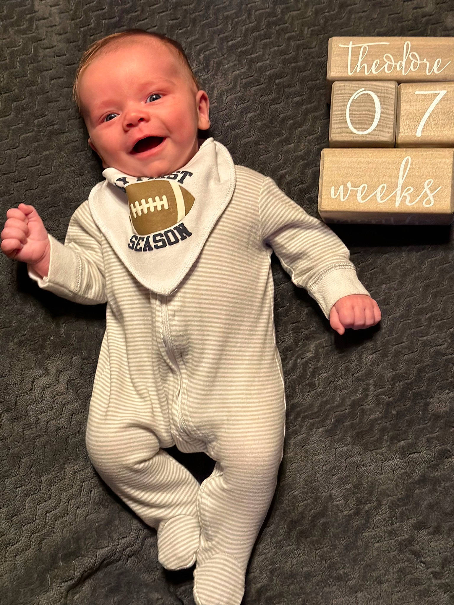 Theodore is registered to the contest to win money with this photo: baby, baby_toddler_clothing, cheek, child, collar, face, finger, flooring, formal_wear, gesture, hand, happy, long_sleeved_t_shirt, pattern, person, sleeve, smile, t_shirt, thumb, toddler
