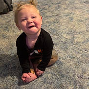 Isabella joined the competition — help win amazing prizes! toddler, child, smiling, sitting, carpet, indoor, baby_gate, storage_drawer, black_shirt, blond_hair, pigtails, happy, person, floor, room, casual_clothing, footwear, playful, cute, young_child