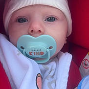 Axel participe au concours pour gagner de l'argent avec cette photo : baby, pacifier, hat, blanket, clothing, red, white, face, infant, closeup, blue_eyes, knit_hat, cozy, child, baby_bottle, soft, portrait, car_seat, newborn, cute