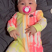 Emma joined the competition — help win amazing prizes! baby, infant, pacifier, headband, flower, tie_dye, onesie, clothing, blanket, bed, cute, child, portrait, indoor, sleepwear, relaxed, soft, pink, yellow, white