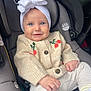 baby, child, car_seat, headband, sweater, smile, blue_eyes, clothing, infant, cute, comfort, seat, cozy, portrait, person, knitwear, white_bow, happy, indoor, casual