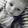 baby, infant, child, portrait, close_up, wide_eyed, lying_down, striped_clothing, onesie, blanket, cushion, bed, indoor, black_and_white, yellow_hearts, heart_stickers, face, eyes, cute, photography