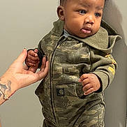 Famous joined the competition — help win amazing prizes! child, toddler, baby, standing, portrait, camouflage, jumpsuit, boots, yellow_boots, indoor, hallway, wall, floor, adult_hand, support, curly_hair, facial_expression, full_body, fashion, cute