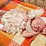 Novalee joined the competition — help win amazing prizes! baby, sleeping, infant, hat, flower_hat, floral_dress, blanket, orange, yellow, patterned_blanket, cute, peaceful, smiling, hand_near_face, soft_lighting, indoors, cozy, child, newborn, resting