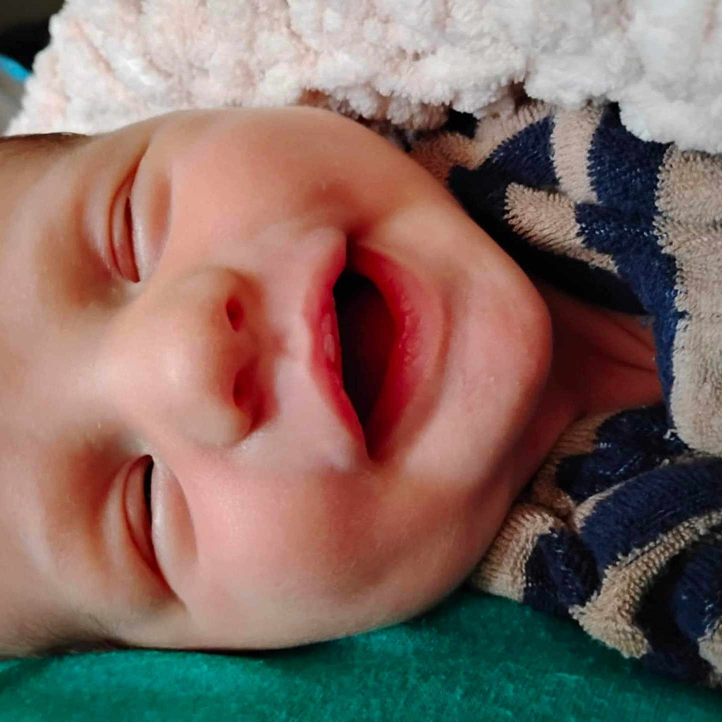 Asher is registered to the contest to win money with this photo: baby, blanket, closeup, clothing, comfort, cozy, cuteness, face, head, human, infant, nap, peaceful, portrait, rest, skin, sleeping, smile, striped, young_child