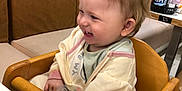 Nevaeh-Rae is registered to the contest to win money with this photo: toddler, child, high_chair, smiling, indoor, restaurant, wooden_chair, blond_hair, baby_clothes, happy, table, condiments, menu, seatbelt, cute, person, face, hair, jacket, food