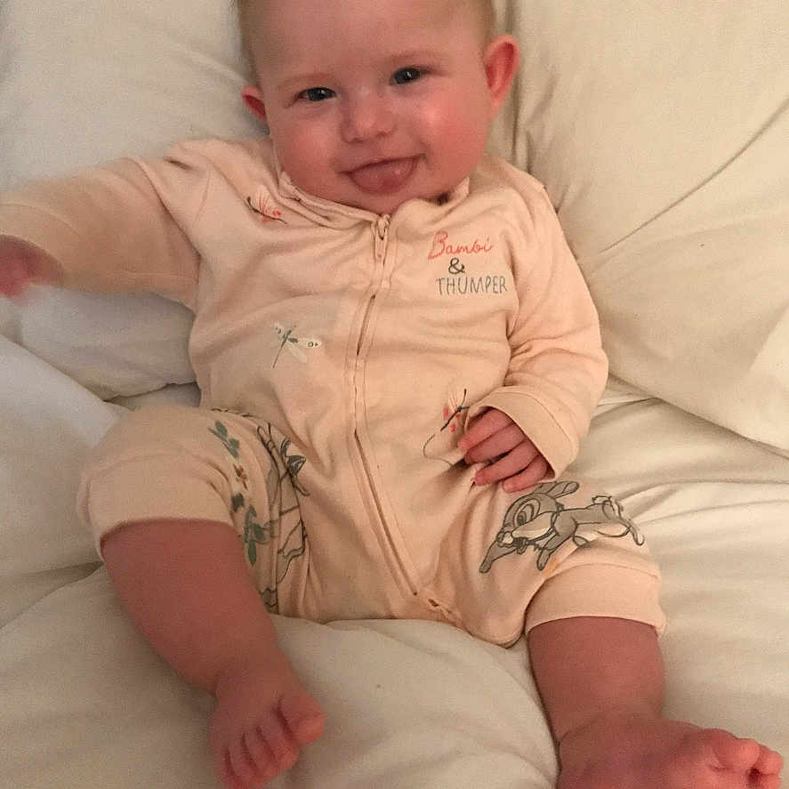 Nevaeh-Rae is registered to the contest to win money with this photo: baby, child, clothing, cozy, cute, expression, face, foot, hand, happy, indoors, infant, onesie, portrait, sitting, smile, soft_surface, tongue_out, white_background, young_child