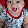 Jesse joined the competition — help win amazing prizes! baby, child, red_hat, smiling, laughing, toy, hand, person, indoor, shirt, clothing, face, eyes, mouth, candid, sitting, cute, happy, playful, infant